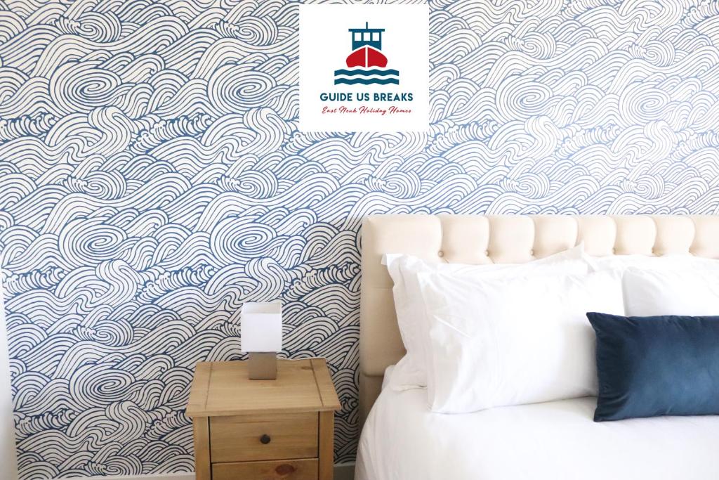a bedroom with a bed and a blue and white wave wallpaper at The Lookout in Cellardyke