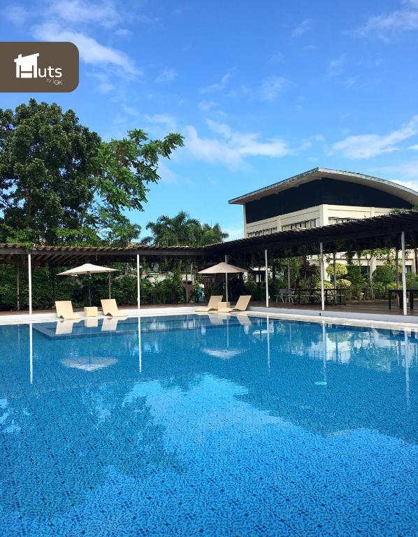 a swimming pool with chairs and umbrellas in front of a building at Huts by Little Green Kitchen in Utap