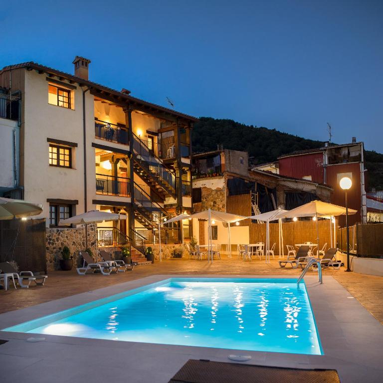 a swimming pool in front of a building at night at Natural&Mente Apartamentos Valle del Jerte in El Torno