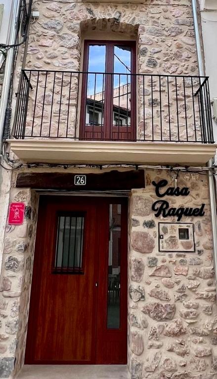 a building with a red door and a balcony at Casa Raquel Montanejos in Montanejos