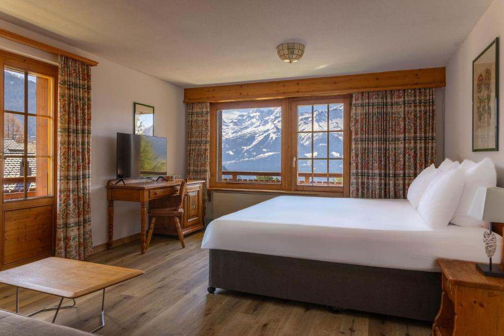a bedroom with a bed and a desk and a window at Hotel Montpelier in Verbier