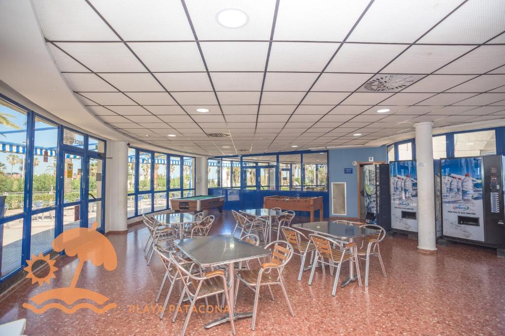a cafeteria with tables and chairs and windows at Patacona Resort Apartments Primera Linea in Valencia