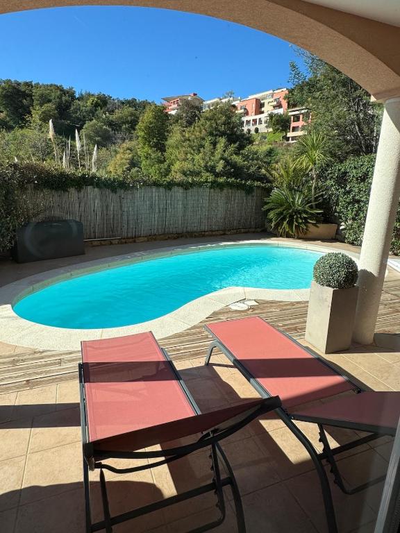 - deux chaises et une piscine dans la cour dans l'établissement Rez de jardin, piscine privative résidence de standing, à Mandelieu-la-Napoule
