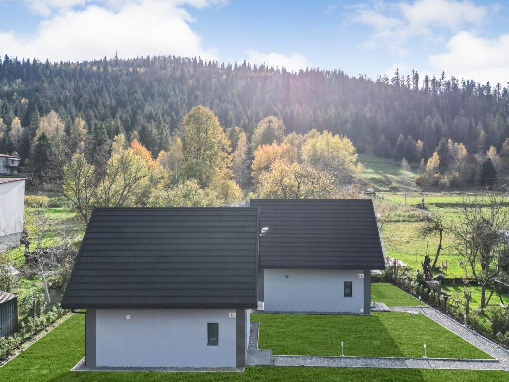a white house with a black roof in a field at Wiślańska Dolina in Wisła