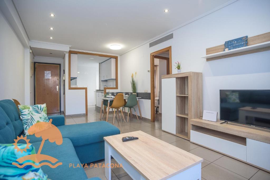 a living room with a blue couch and a tv at Patacona Resort Apartments Primera Linea in Valencia