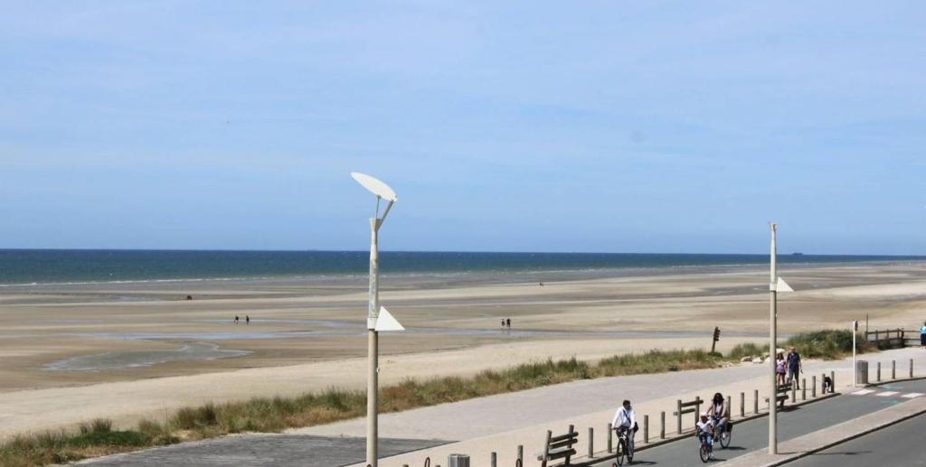 une plage avec des gens faisant du vélo sur une route dans l'établissement Apartment with balcony on the seafront, à Neufchâtel-Hardelot