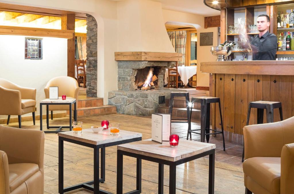 a bar with tables and a fireplace in a restaurant at Hotel Montpelier in Verbier