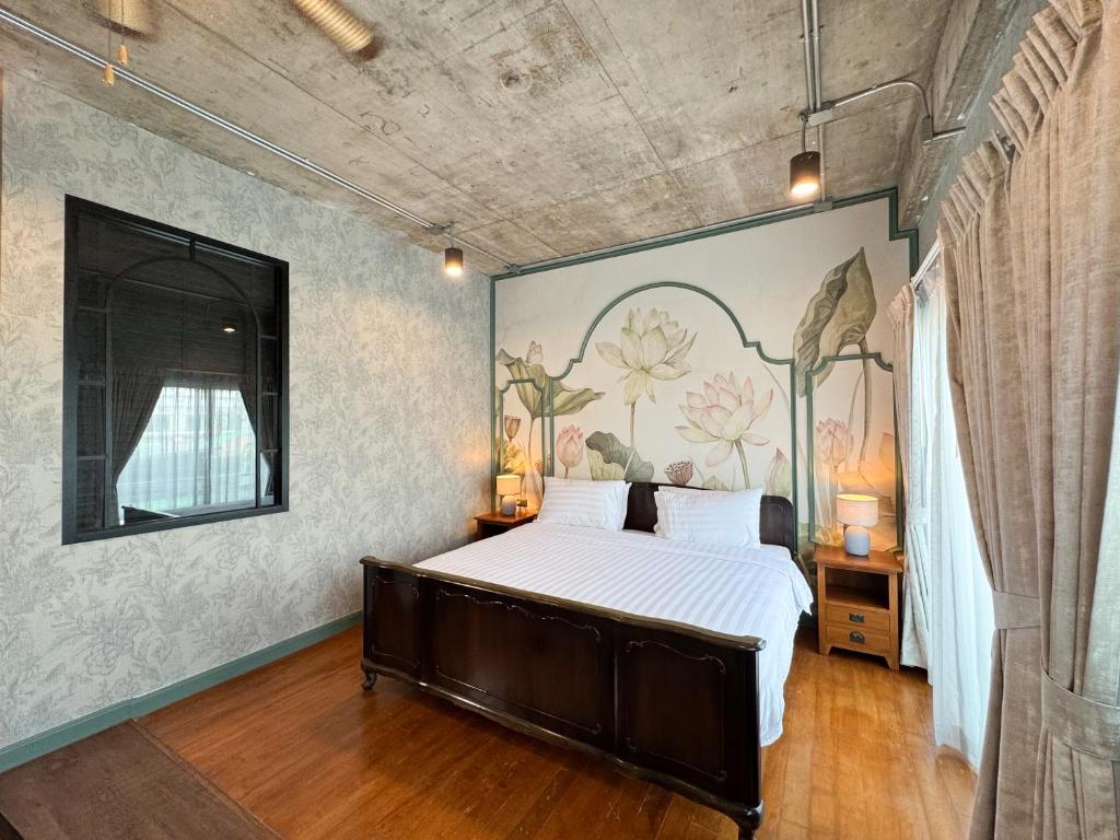 a bedroom with a large bed with a painting on the wall at Nara Poshtel Sathorn in Bangkok
