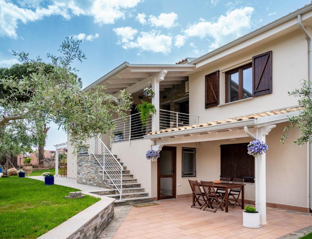 Ein weißes Haus mit einer Terrasse und einem Tisch in der Unterkunft La Botte e il Vino Rooms in Capoterra