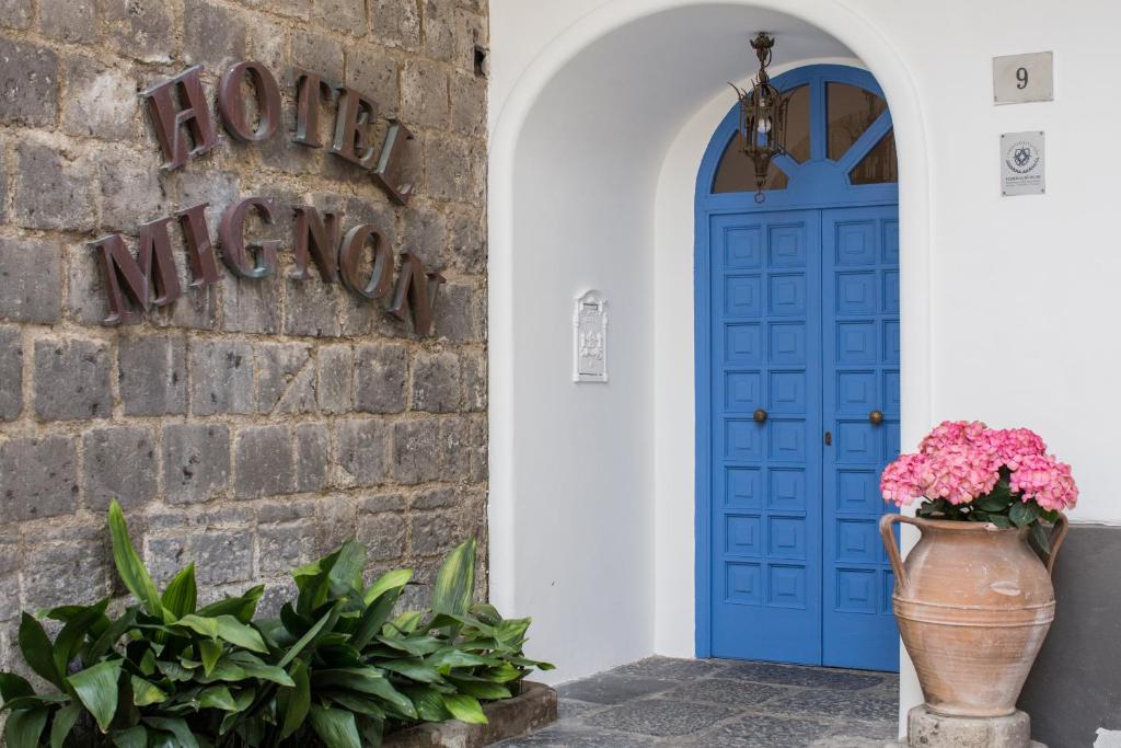 una puerta azul y un jarrón de flores delante de un edificio en Hotel Mignon Meublè en Sorrento