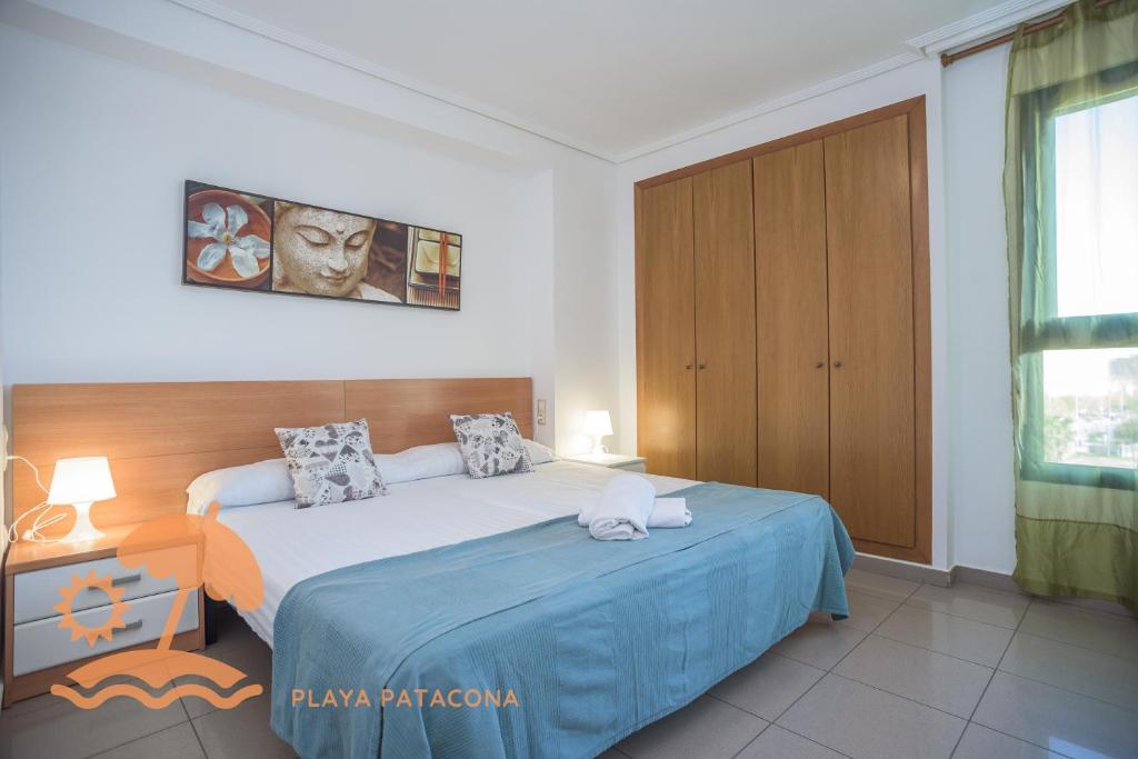 a bedroom with a large bed with a blue blanket at Patacona Resort Apartments Primera Linea in Valencia