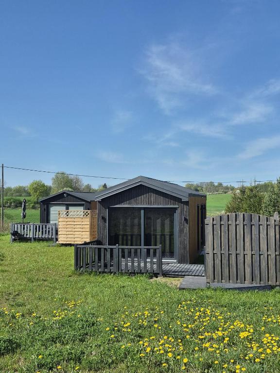 a wooden house with a fence in a field at Cichy Brzeg Mazurski in Popowo Salęckie