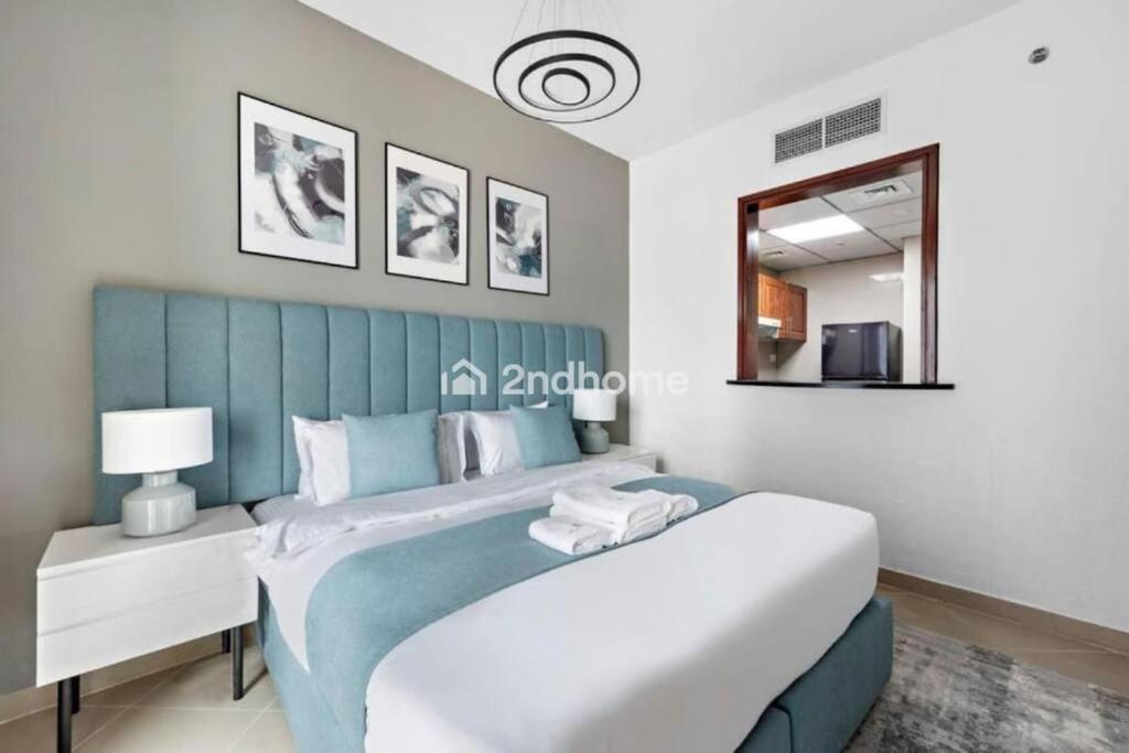 a bedroom with a blue and white bed and a mirror at Luxury Unit Located in Icon Tower, JLT in Dubai