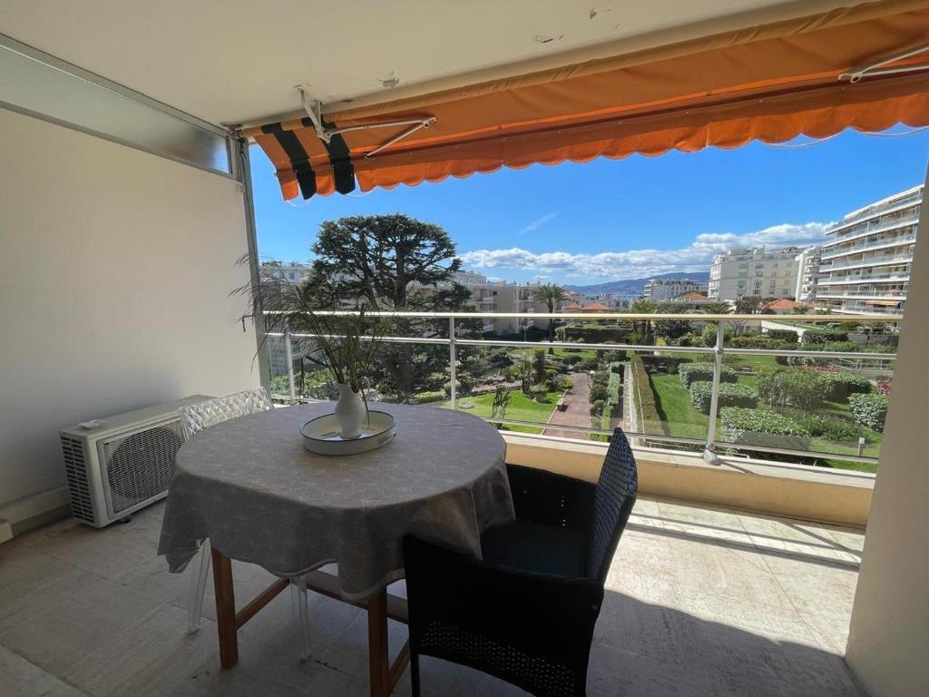 une table et des chaises dans une pièce avec une grande fenêtre dans l'établissement Croisette and beaches. View on gardens and sea., à Cannes