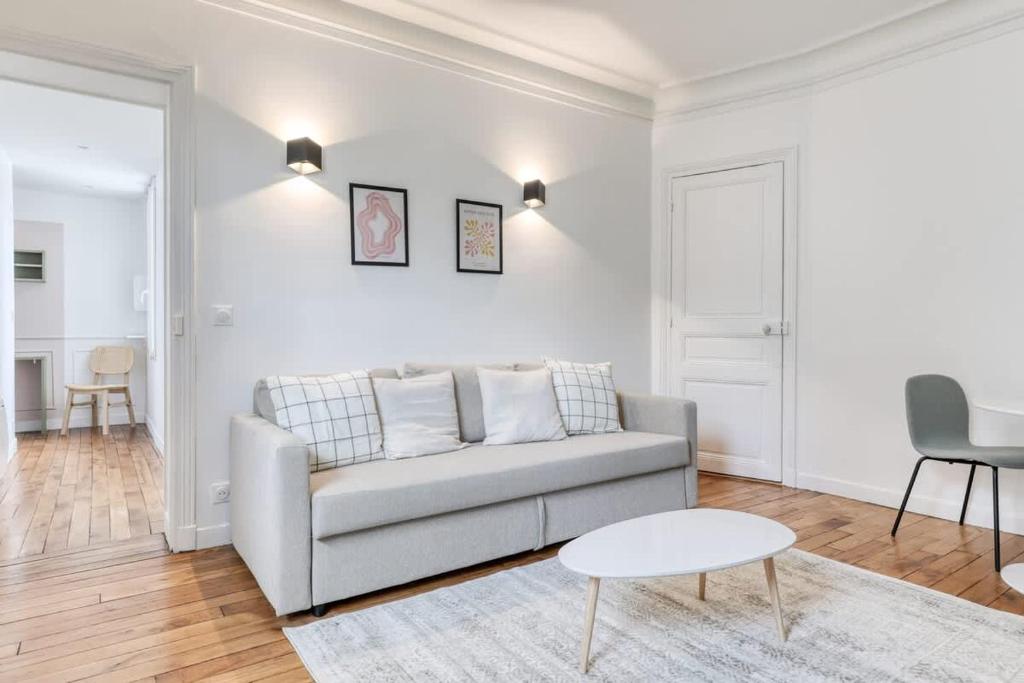 un salon blanc avec un canapé et une table dans l'établissement Delta - Appartement parisien - 9e, à Paris