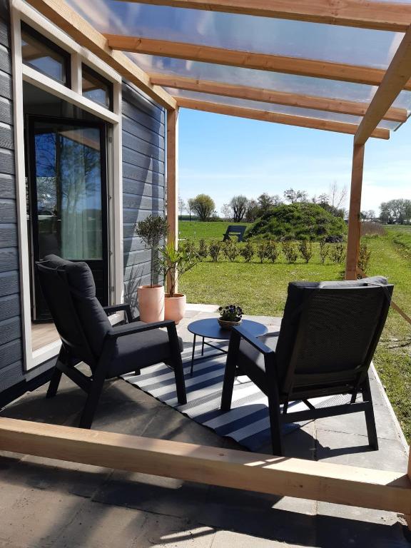 a patio with two chairs and a table on a porch at B&B weidse blik Ingelum in Engelum