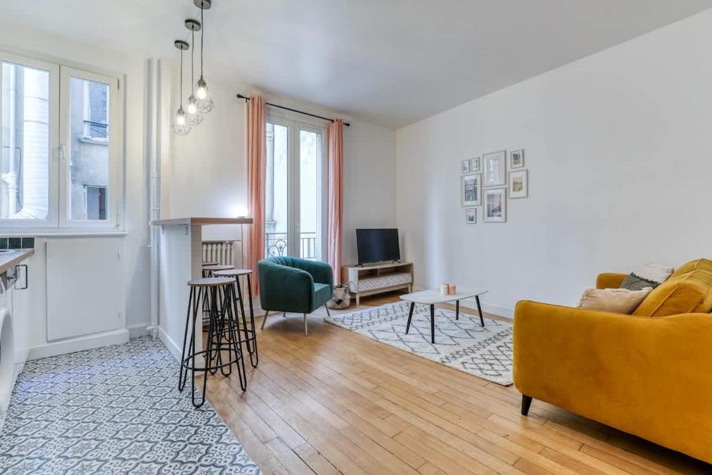 un salon avec un canapé jaune et une télévision dans l'établissement Poissonniere -Cosy apartment near Montmartre, à Paris