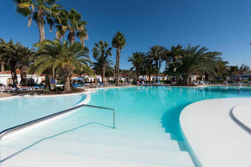 una gran piscina con palmeras en un complejo en eó Suite Hotel Jardin Dorado, en Maspalomas