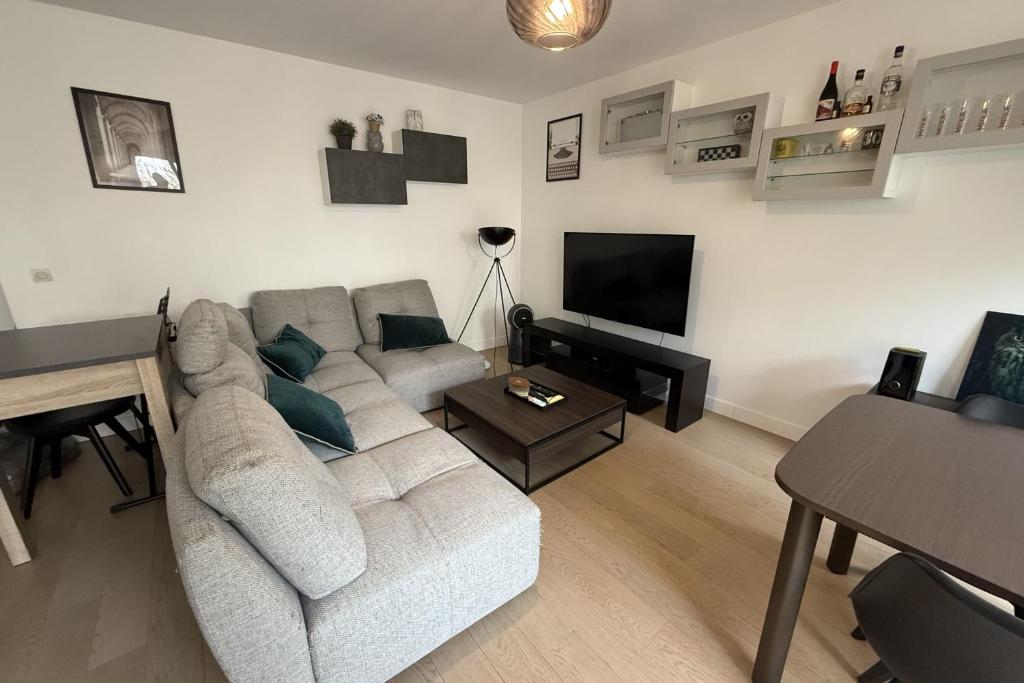 un salon avec un canapé et une télévision dans l'établissement 2-bedroom apartment - near park, à Issy-les-Moulineaux
