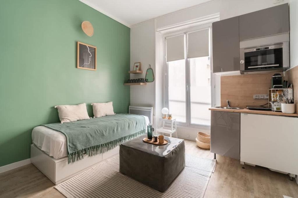 - une chambre avec des murs verts, un lit et une table dans l'établissement 11 Joubert - Joli studio 1PAX Galeries Lafayette, à Paris