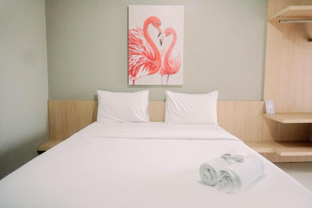 当格浪Comfort 2BR at 3rd Floor Baileys Apartment By Travelio的卧室里有一张白色的床和两只粉色的火烈鸟