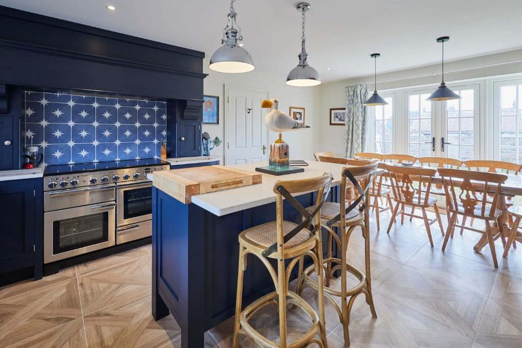 a kitchen with blue cabinets and a table with chairs at Host & Stay - Kittiwake Cottage in Bridlington