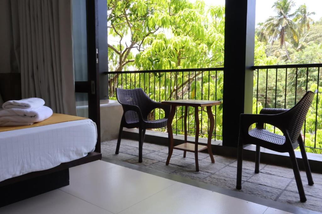 a bedroom with a table and chairs and a balcony at Handagedara Resort & Spa in Mirissa