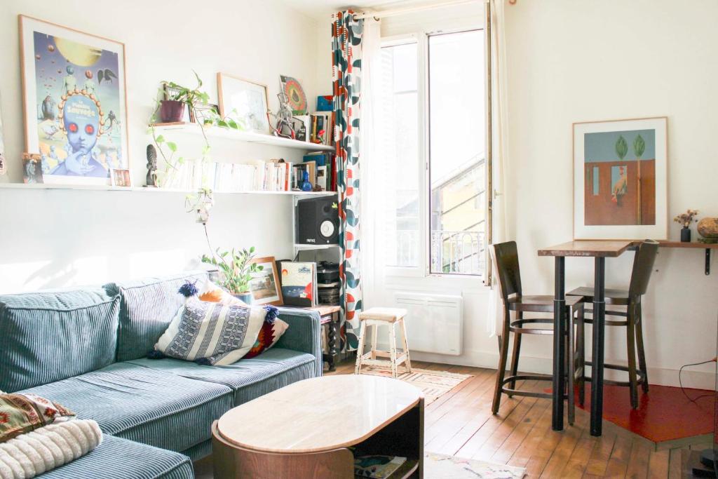 un salon avec un canapé bleu et une table dans l'établissement Renovated apartment for 4 people, à Pantin