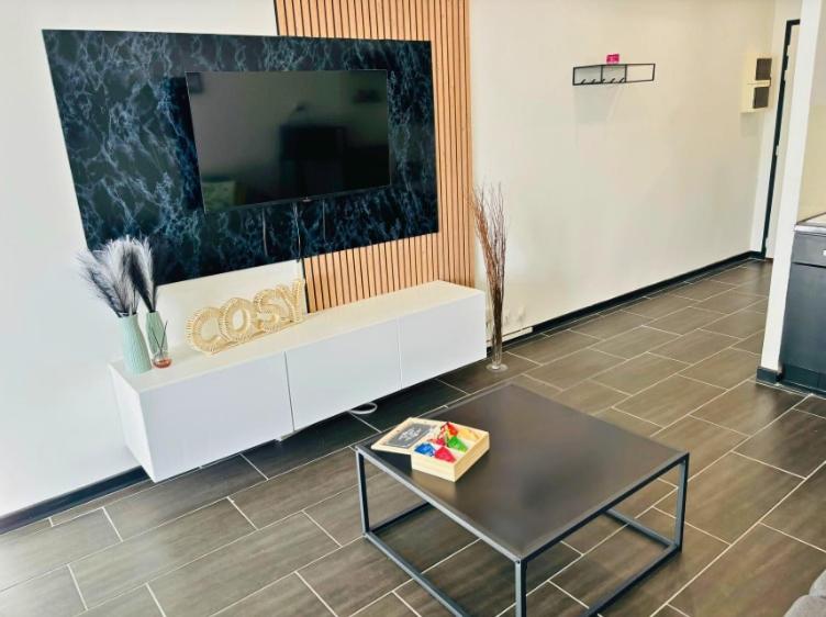 - un salon avec une grande télévision et une table dans l'établissement Le Cosy I Studio, à Annemasse