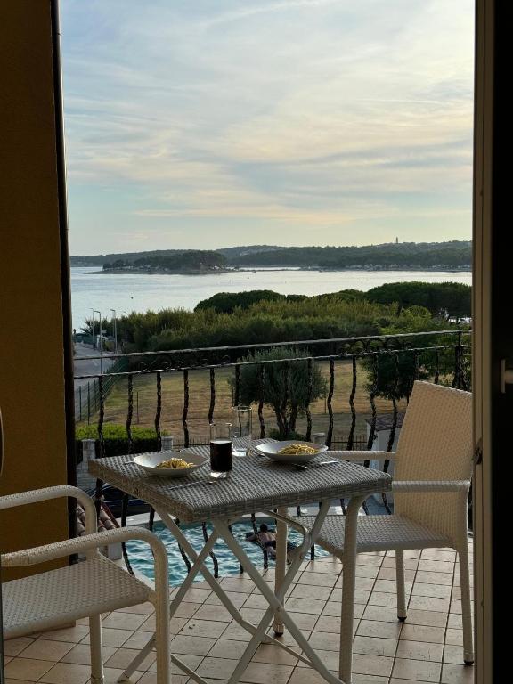 a table and chairs on a balcony with a view of the ocean at Apartment Mali raj in Medulin