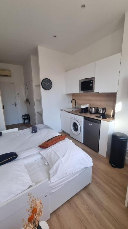 Cet appartement comprend une chambre avec un lit blanc et une cuisine. dans l'établissement Studio Beitz Calme Proche Gare, à Bordeaux