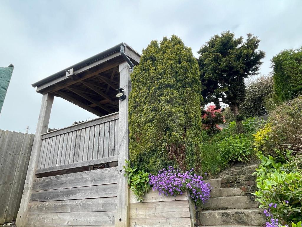 ein Garten mit einem Holztor und einer Treppe mit Blumen in der Unterkunft Gorwel, Spacious 3 Bedroom Cottage near the Beach in Llanarth