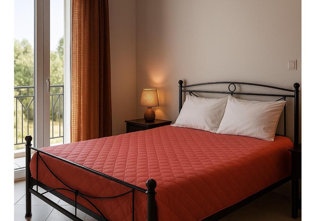 una camera da letto con un letto con un piumone arancione e una finestra di Ammodares a Lixouri