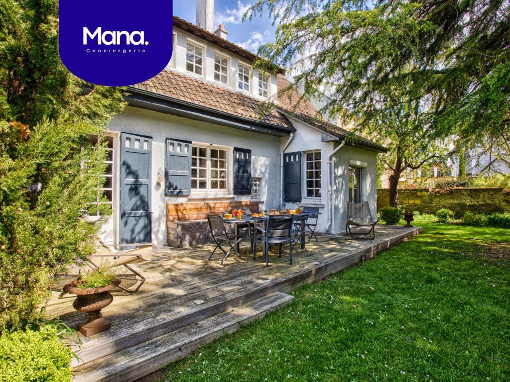 une terrasse arrière avec une table et des chaises dans l'établissement Maison famille - Centre Ville - Jardin Botanique, à Cabourg