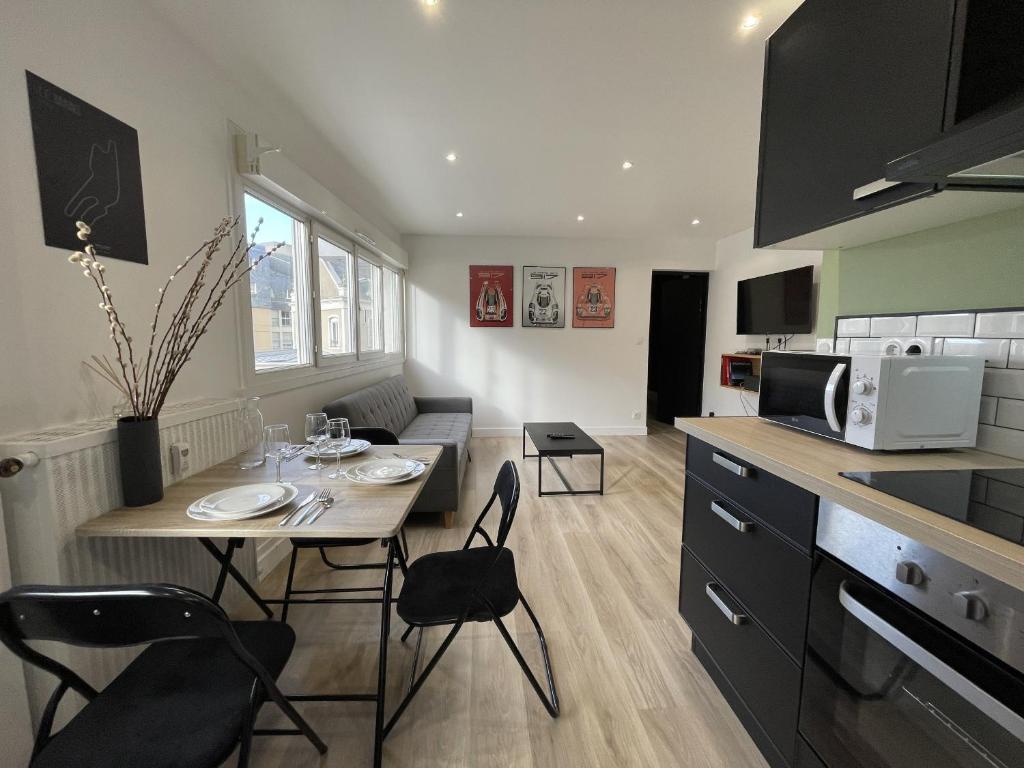 une cuisine avec une table avec des chaises et un micro-ondes dans l'établissement Le Scudéria - Centre - 3p - Rêve au Mans, au Mans