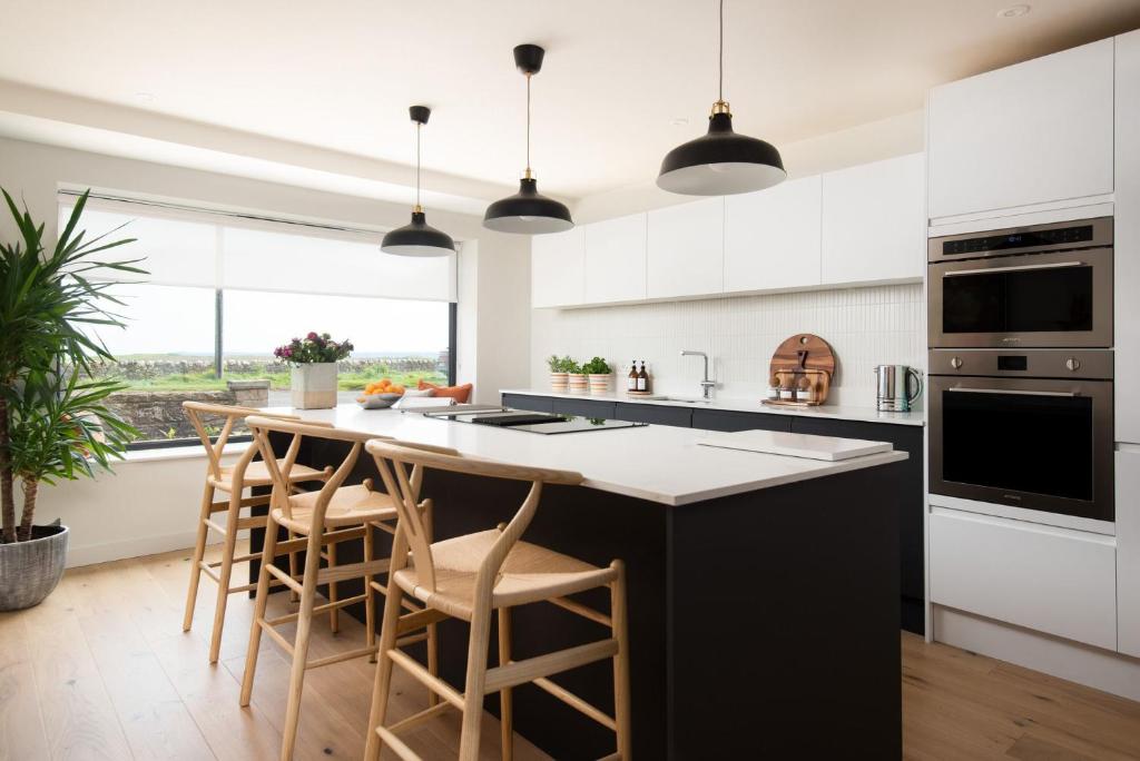 een keuken met witte kasten en een groot eiland met barkrukken bij Tide's Watch in Beadnell