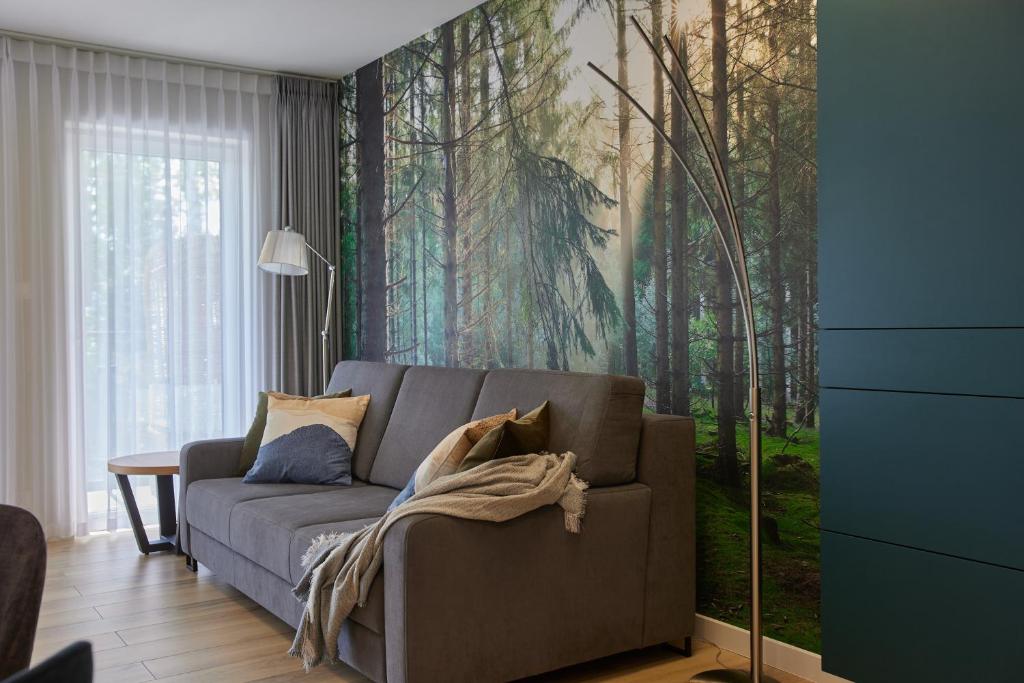 a living room with a couch and a forest mural at Forest Apartment in Pobierowo