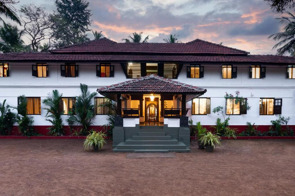 a large white house with a front door at SaffronStays Amaya - 5BR 300-year-old Kerala-style heritage home near Kannur Airport in Irikkūr