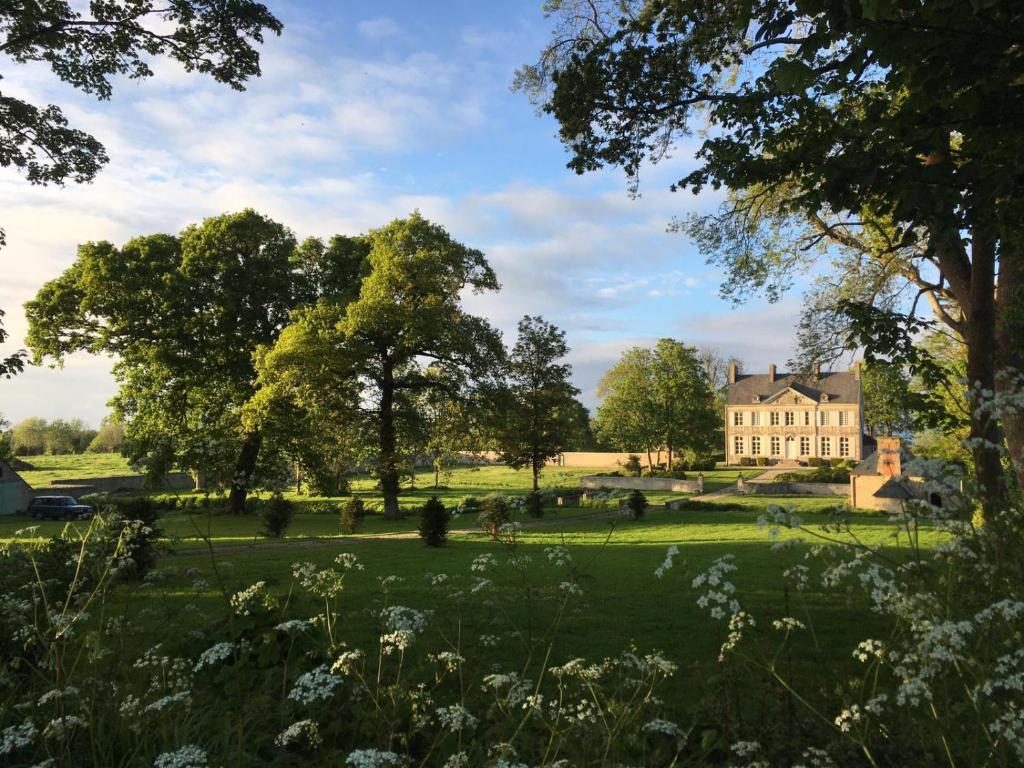 une maison au milieu d'un champ avec des arbres dans l'établissement Chateau de Gourmont Dream Stay in a Norman Castle, à Saint-Germain-de-Varreville