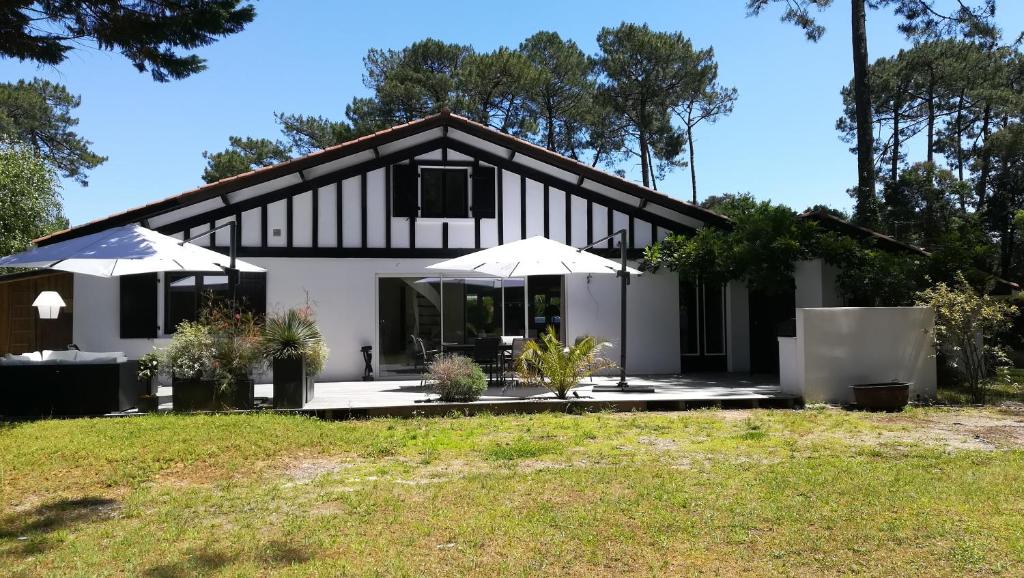 une maison avec deux parasols blancs devant elle dans l'établissement Havre de paix à 2kms de la plage, à Ondres