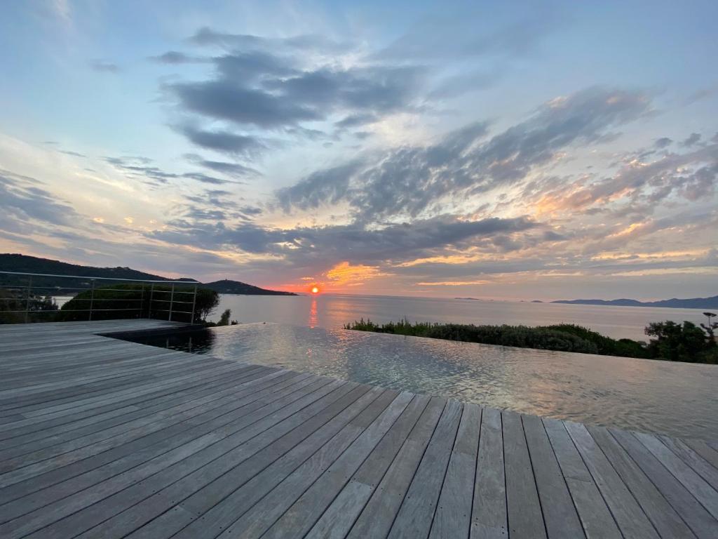un coucher de soleil sur un plan d'eau avec une terrasse en bois dans l'établissement Casa Bianchina Corsica, à Coti-Chiavari