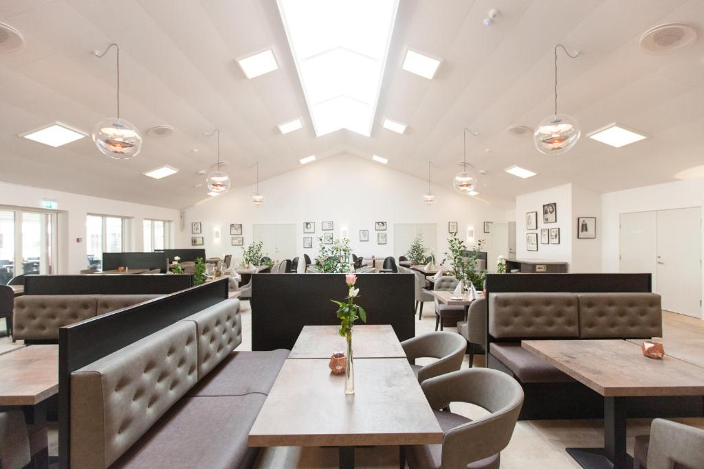 a dining room with tables and chairs and lights at Hotel Falster in Nykøbing Falster