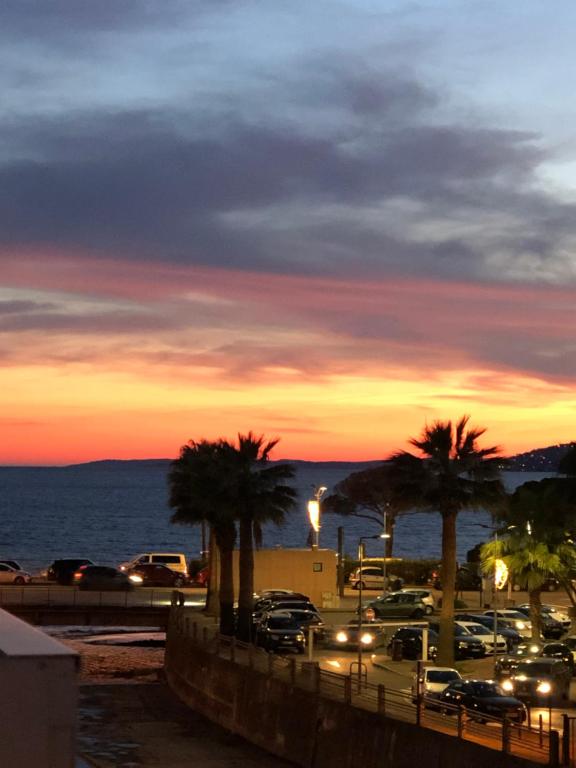 - un parking avec des voitures et des palmiers au coucher du soleil dans l'établissement Villa pallazzino, à Saint-Raphaël
