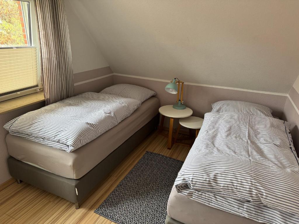 a room with two beds and a table with a lamp at Christiansand in Norddorf