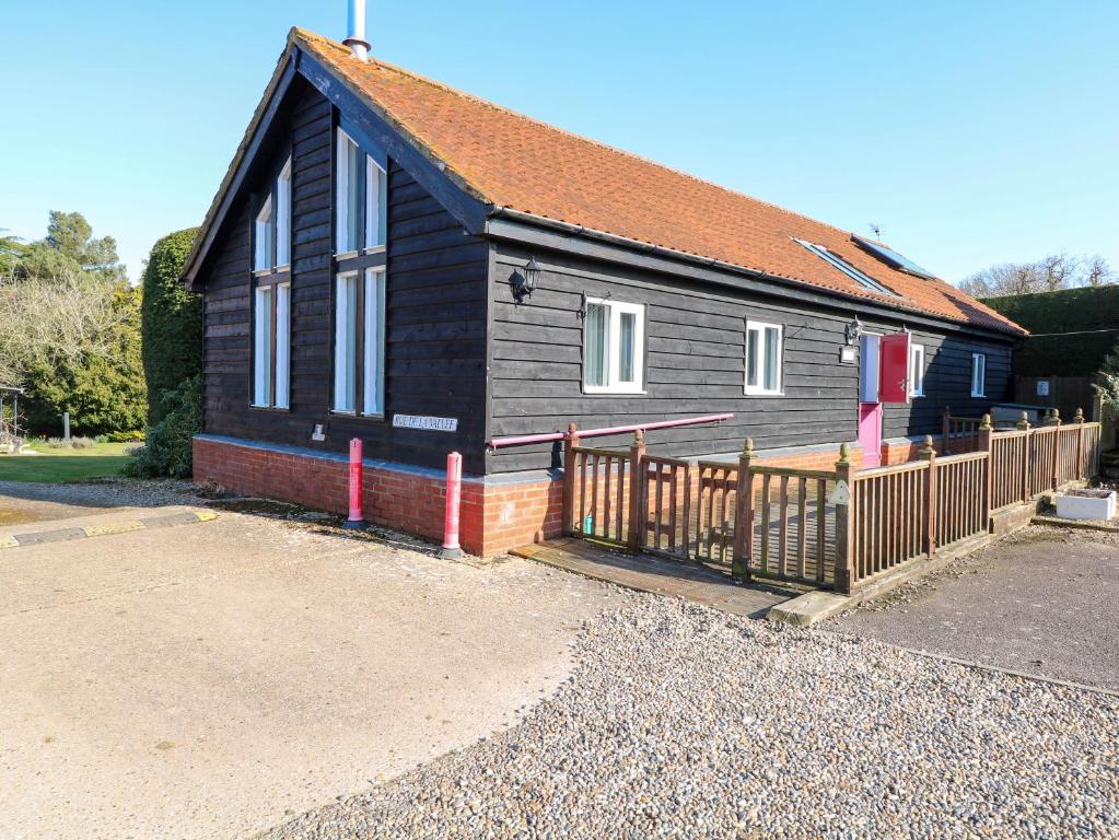 une maison noire avec une clôture en bois devant elle dans l'établissement Rookyard Cottage, à Halesworth