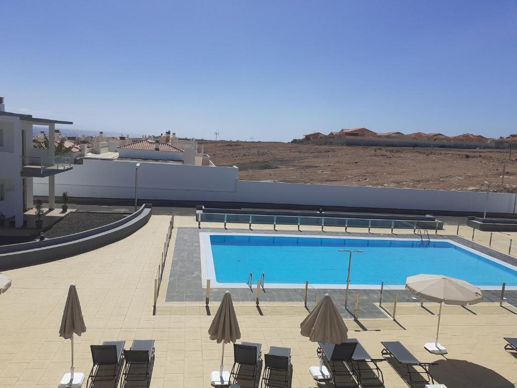 a swimming pool with chairs and umbrellas next to a building at Like at Home in Costa de Antigua