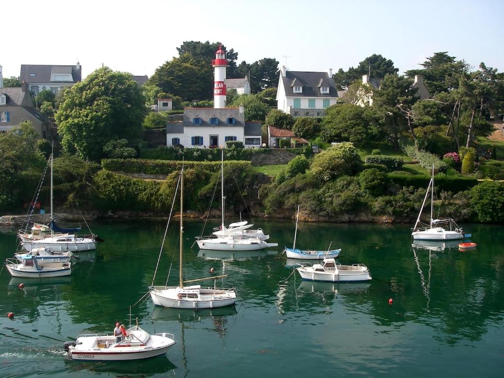 un groupe de bateaux dans une masse d'eau avec phare dans l'établissement DOELAN superb apartment with sea views on all sides, à Clohars-Carnoët