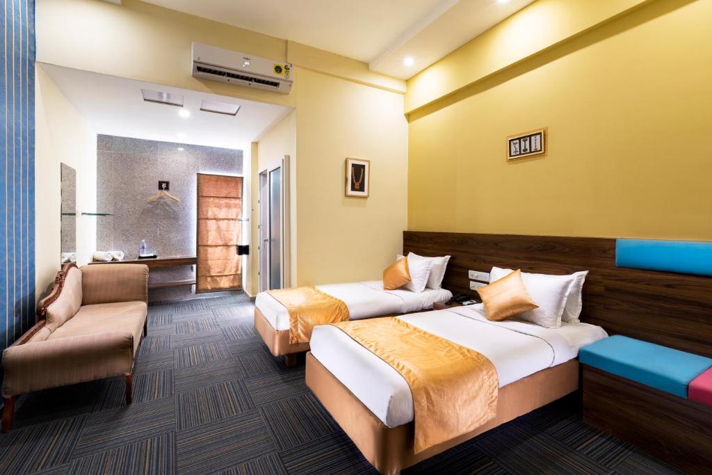a hotel room with two beds and a couch at juSTa Sarang, Rameswaram in Rāmeswaram