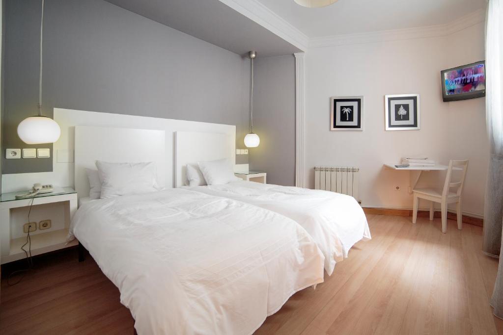 Schlafzimmer mit einem großen weißen Bett und einem Schreibtisch in der Unterkunft Hostal Adriano in Madrid