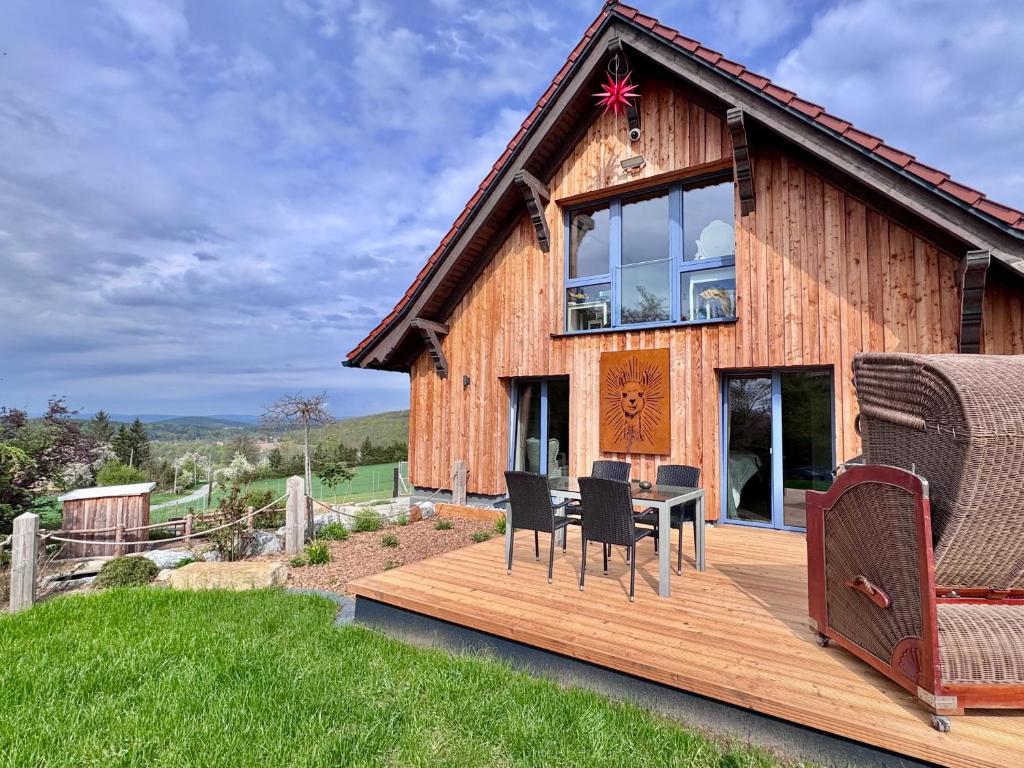 a wooden house with a table and chairs on a deck at TOP moderne FeWo - Alpakahof zum Himmelreich, traumhafte Lage, Terrasse mit Weitblick, kostenfreier Parkplatz, Nähe Kurklinik, optional Sauna in Bad Gottleuba